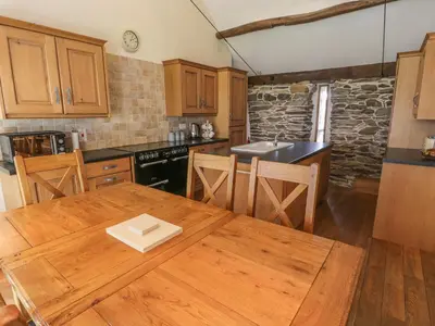 a kitchen with wooden cabinets and a wooden table at Hendoll Barn in Fairbourne