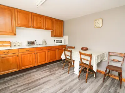 a kitchen with wooden cabinets and a table with chairs at Holly Farm Cottage in Newbridge on Wye