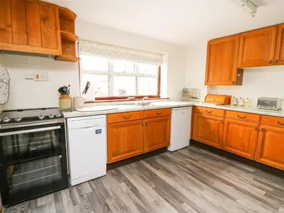 a kitchen with wooden cabinets and white appliances at Holly Farm Cottage in Newbridge on Wye