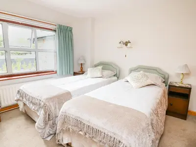 two beds in a white room with a window at Holly Farm Cottage in Newbridge on Wye