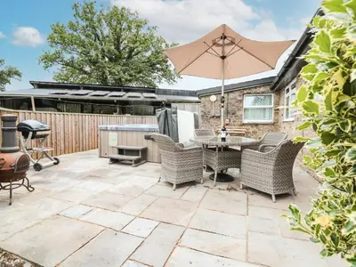 a patio with a table and chairs and an umbrella at Holly Farm Cottage in Newbridge on Wye