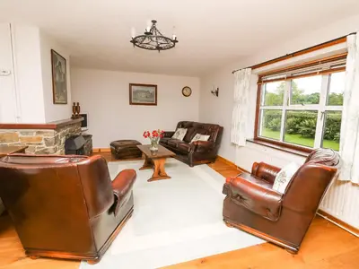 a living room with leather chairs and a fireplace at Holly Farm Cottage in Newbridge on Wye