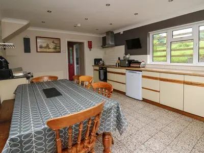 a kitchen and dining room with a table and chairs at Aberdauddwr in Llanwnen