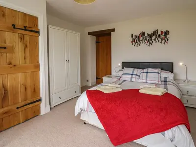 a bedroom with a bed with a red blanket on it at Aberdauddwr in Llanwnen