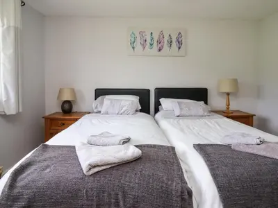 two beds in a bedroom with towels on them at Aberdauddwr in Llanwnen