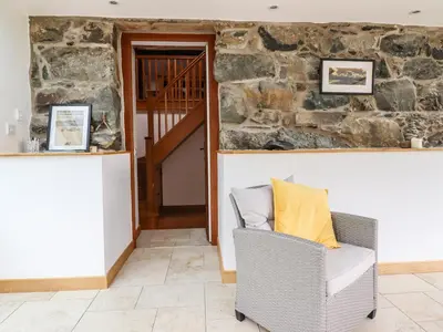 a room with a chair and a stone wall at Ysgubor Las in Dolgellau