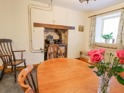 a dining room with a table and a fireplace at Tanyrallt Farm in Beulah