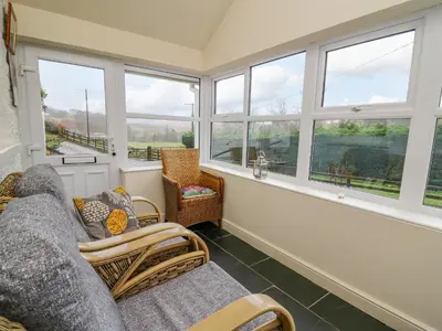 a living room with windows and a couch and chairs at Tanyrallt Farm in Beulah