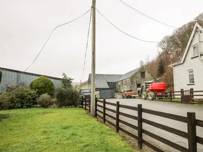 a farm with a fence and a house and a truck at Tanyrallt Farm in Beulah