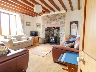 a living room with couches and a stone fireplace at Groes Lwyd in Gwyddelwern