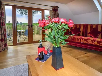 a living room with a vase with pink flowers on a table at Brynhir Farm in Llandrindod Wells