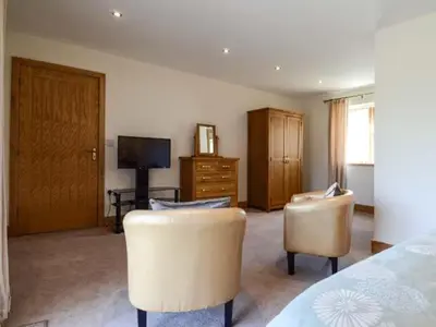 a bedroom with two chairs and a bed and a television at Brynhir Farm in Llandrindod Wells