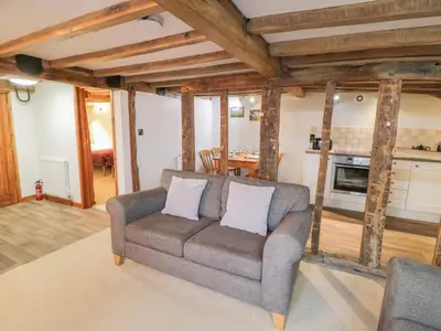 a living room with a couch and a kitchen at The Barley Store in Craven Arms