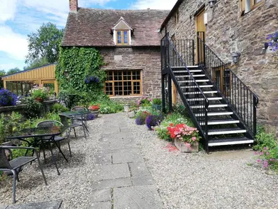 a stone building with a staircase and tables and chairs at The Barley Store in Craven Arms