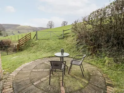 a table and two chairs sitting next to a field at Peniarth in Pen-y-bont-fawr
