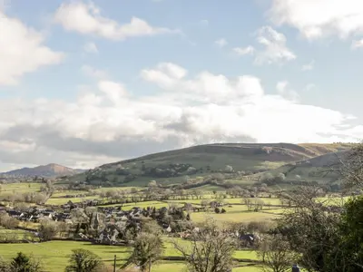 a green hillside with a village in the foreground at Peniarth in Pen-y-bont-fawr