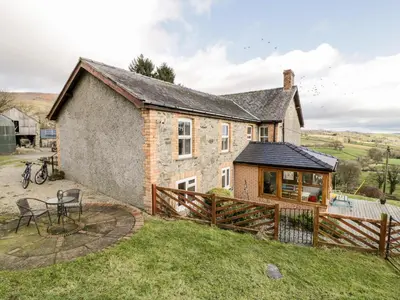 a large stone house with a wooden fence at Peniarth in Pen-y-bont-fawr