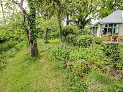 a garden path leading to a house with trees and flowers at Hill Brow in Acton Scott