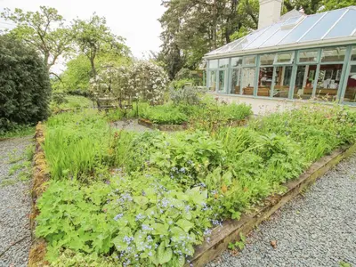 a garden in front of a greenhouse at Hill Brow in Acton Scott