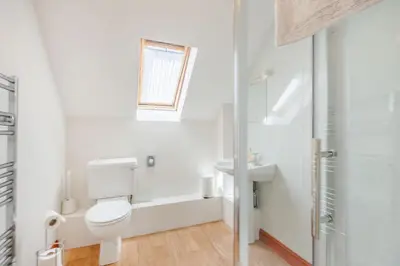 a white bathroom with a toilet and a sink at Byne Brook Cottage in Wistanstow