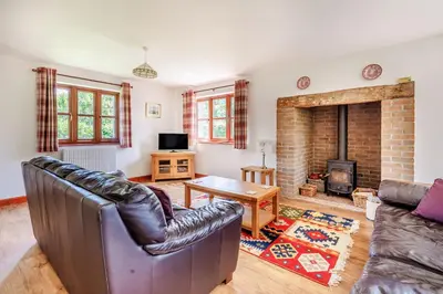a living room with a couch and a fireplace at Byne Brook Cottage in Wistanstow
