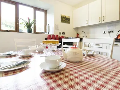 a kitchen with a table with a table cloth on it at Little Cow House in Chirk