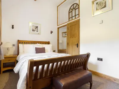 a bedroom with a bed with a bench and a mirror at Little Cow House in Chirk