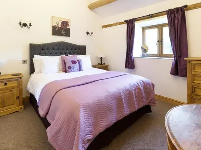 a bedroom with a large bed with a pink blanket at Little Cow House in Chirk