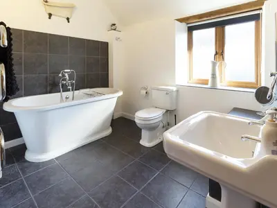 a bathroom with a tub and a toilet and a sink at Little Cow House in Chirk