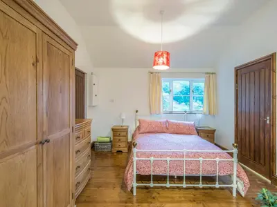 a bedroom with a bed and a dresser and a window at Woodpeckers Cottage in Church Stretton