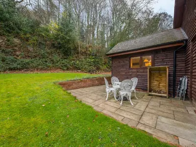 a patio with a table and chairs next to a building at Woodpeckers Cottage in Church Stretton