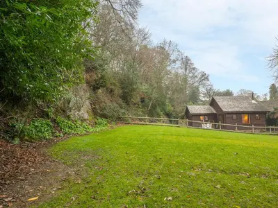 a green field with a house and a fence at Woodpeckers Cottage in Church Stretton