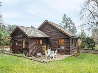 a small wooden house with two chairs and a patio at Woodpeckers Cottage in Church Stretton