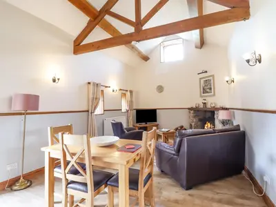 a dining room and living room with a table and chairs at Bwthyn Ty Newydd in Pont Dolanog