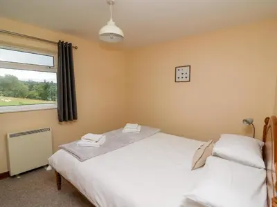 a bedroom with two beds and a window at Red Kite Cottage in Llandrindod Wells
