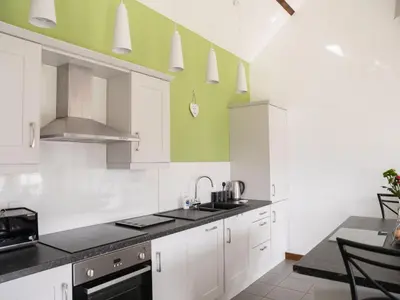 a kitchen with white cabinets and green walls at 2 Beacon View Barn in Felindre