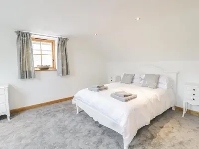 a white bedroom with a white bed and a window at Sgubor in Llangwm