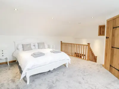 a bedroom with a white bed and a wooden door at Sgubor in Llangwm