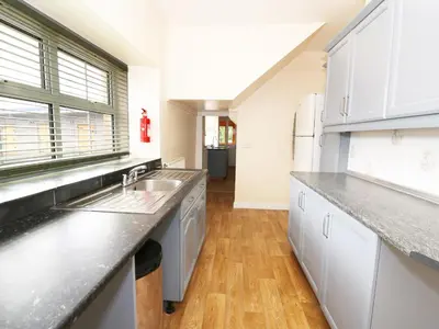 a kitchen with white cabinets and a wooden floor at Dolau Farmhouse in Llanwnen