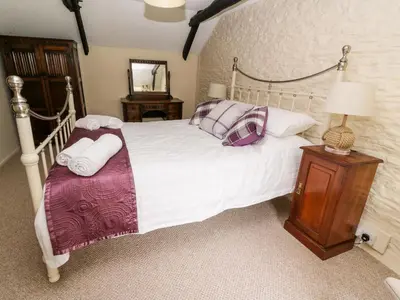 a bedroom with a white bed with purple pillows at Dolau Farmhouse in Llanwnen
