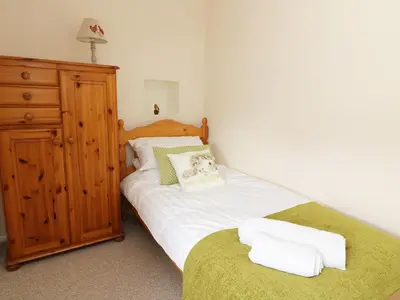 a bedroom with a bed with white sheets and a dresser at Dolau Farmhouse in Llanwnen
