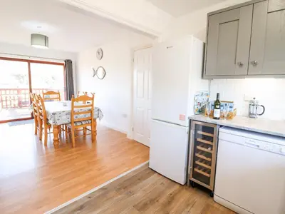 a kitchen with white appliances and a dining room with a table at Sealyons in Fairbourne