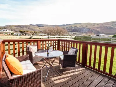 a patio with a table and chairs on a deck at Sealyons in Fairbourne