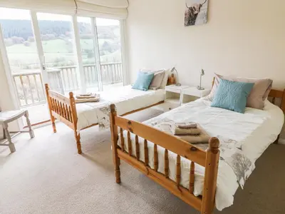 a bedroom with two beds and a large window at Middle Hivron in Bleddfa