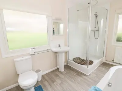 a white bathroom with a shower and a toilet and a sink at Middle Hivron in Bleddfa