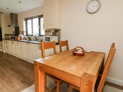 a kitchen with a wooden table and a clock on the wall at Caban Nant Ddu in Nantmel