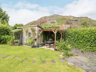 a stone cottage with a table in a garden at Bodywen in Llangynog