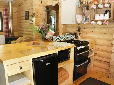 a kitchen in a log cabin with a stove at Wilderness Lodge in Shelve