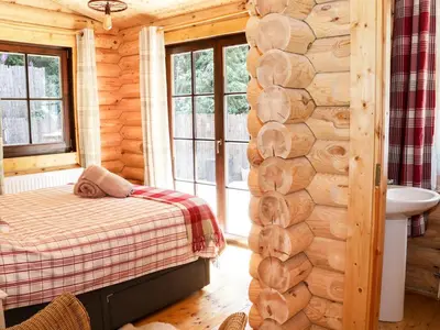 a bedroom in a log cabin with a bed and a sink at Wilderness Lodge in Shelve