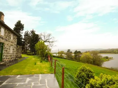 a view of a house with a fence and a lake at Ffynnon Gower in Llangower